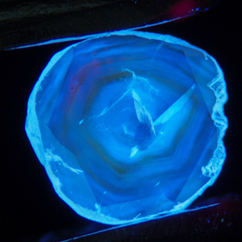 Natural diamond under long wave ultraviolet lighting shows the growth zoning (x15 magnification).