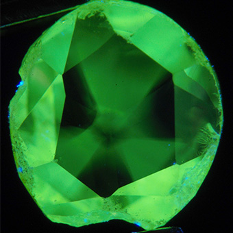 Natural diamond under long wave ultraviolet lighting shows 3 growth sector (x15 magnification).